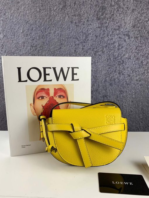 LOEWE Gate Mini Grained-Leather Cross-Body Bag. Original Quality Bag. Authentic Style. Genuine Calf Leather. Metal Hardware. Authentic Packaging. Original Quality Dust Bag. Loewe brings signature finesse to the micro-mini bag trend with this tiny red iteration of its coveted Gate style. The bag takes inspiration from countryside gate latch fastenings to create this grained-leather Gate cross-body bag. It's crafted to a half-moon shape with a long shoulder strap that is finished with black lacquered edges, then opens to reveal a suede interior with a single slip pocket. | CRIS&COCO Store | High Quality Designer Handbag