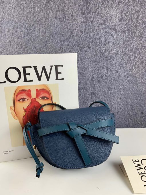 LOEWE Gate Mini Grained-Leather Cross-Body Bag. Original Quality Bag. Authentic Style. Genuine Calf Leather. Metal Hardware. Authentic Packaging. Original Quality Dust Bag. Loewe brings signature finesse to the micro-mini bag trend with this tiny red iteration of its coveted Gate style. The bag takes inspiration from countryside gate latch fastenings to create this grained-leather Gate cross-body bag. It's crafted to a half-moon shape with a long shoulder strap that is finished with black lacquered edges, then opens to reveal a suede interior with a single slip pocket. | CRIS&COCO Store | High Quality Designer Handbag