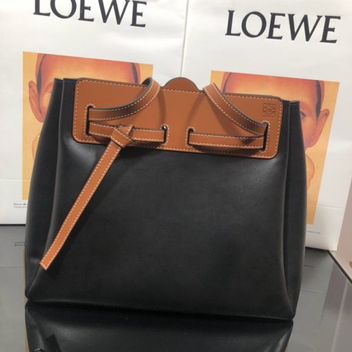 LOEWE Lazo Top Handle Bag. Authentic Quality Bag with literature, gift box, dust bag and authenticity card. A highly chic and sophisticated bag, the Lazo features the recognizable emblematic Gate knot. Contrasting calfskin straps holds the bag, cinching to fasten the bag effortlessly. Creating a sinuous accordion soft silhouette with soft natural calfskin, this novel interpretation is the next must-have chic functional bag of the season. The soft and slouchy calfskin bag is devoid of any zips for the closure and instead relies on the contrasting calfskin straps to cinch and fasten the opening. A relaxed update on a classic bag design. | CRIS&COCO Authentic Quality Designer Bags and Luxury Accessories