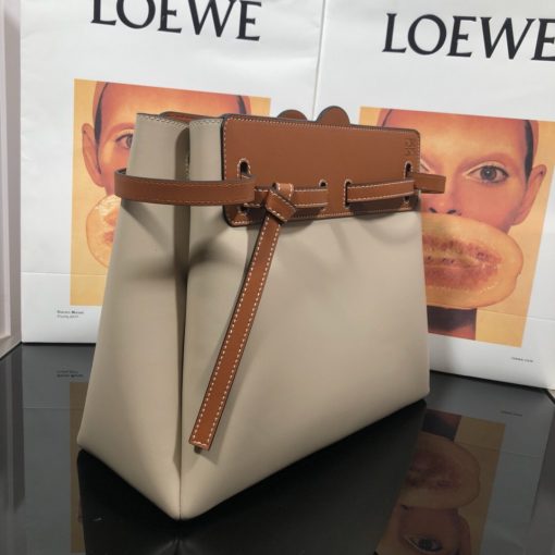 LOEWE Lazo Top Handle Bag. Authentic Quality Bag with literature, gift box, dust bag and authenticity card. A highly chic and sophisticated bag, the Lazo features the recognizable emblematic Gate knot. Contrasting calfskin straps holds the bag, cinching to fasten the bag effortlessly. Creating a sinuous accordion soft silhouette with soft natural calfskin, this novel interpretation is the next must-have chic functional bag of the season. The soft and slouchy calfskin bag is devoid of any zips for the closure and instead relies on the contrasting calfskin straps to cinch and fasten the opening. A relaxed update on a classic bag design. | CRIS&COCO Authentic Quality Designer Bags and Luxury Accessories