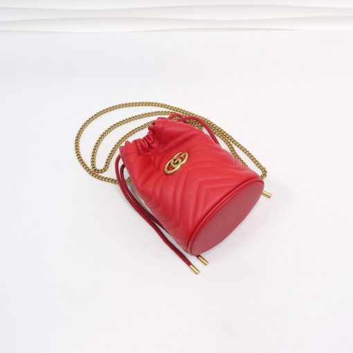 GUCCI GG Marmont Mini Bucket Bag. Original Quality Bag including gift box, literature, dust bag, authenticity card. The world of GG Marmont expands with the introduction of a mini bucket bag shape crafted from Matelassé leather in vibrant tones. Inspired by an archival design from the '70s, a hallmark era of the House, the Double G decorates the front of this accessory. Featuring a chain strap and drawstring closure the versatile shape can be worn as shoulder and as a crossbody bag. | Cris and Coco. High Quality Bags and Luxury Accessories