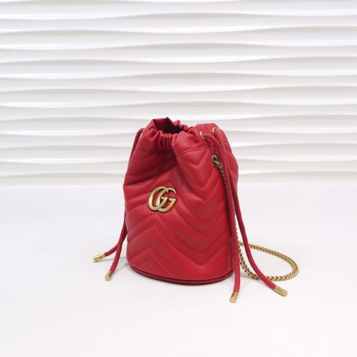 GUCCI GG Marmont Mini Bucket Bag. Original Quality Bag including gift box, literature, dust bag, authenticity card. The world of GG Marmont expands with the introduction of a mini bucket bag shape crafted from Matelassé leather in vibrant tones. Inspired by an archival design from the '70s, a hallmark era of the House, the Double G decorates the front of this accessory. Featuring a chain strap and drawstring closure the versatile shape can be worn as shoulder and as a crossbody bag. | Cris and Coco. High Quality Bags and Luxury Accessories