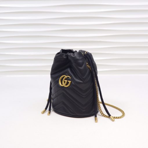 GUCCI GG Marmont Mini Bucket Bag. Original Quality Bag including gift box, literature, dust bag, authenticity card. The world of GG Marmont expands with the introduction of a mini bucket bag shape crafted from Matelassé leather in vibrant tones. Inspired by an archival design from the '70s, a hallmark era of the House, the Double G decorates the front of this accessory. Featuring a chain strap and drawstring closure the versatile shape can be worn as shoulder and as a crossbody bag. | Cris and Coco. High Quality Bags and Luxury Accessories