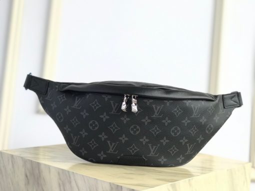 LOUIS VUITTON Discovery Bum Bag. Combining casual sophistication with contemporary practicality, the Discovery Bumbag is the perfect city companion. It is fashioned from Monogram Eclipse canvas/Monogram Shadow leather and adorned with zipped pockets on the front and back for easy access. With its adjustable belt and body-friendly design, it can be worn stylishly slung across the chest, draped over the shoulder or simply strapped around the waist.| CRIS&COCO Authentic Quality Designer Bags and Luxury Accessories