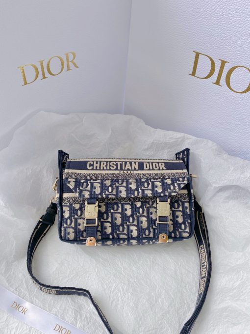 DIOR Small DiorCamp Bag. Original Quality Bag including gift box, care book, dust bag, authenticity card. Maria Grazia Chiuri has updated the classic messenger bag by adding signature Dior details for a relaxed and modern look. Fully embroidered with the Dior Oblique motif, the bag is enhanced by a 'CHRISTIAN DIOR PARIS' signature flap, as well as sportswear-inspired 'CD' buckles. Equipped with an adjustable and removable shoulder strap, the small, compact messenger bag can be worn over the shoulder or crossbody, and will make an ideal urban companion. | CRIS&COCO Authentic Quality Designer Bag and Luxury Accessories