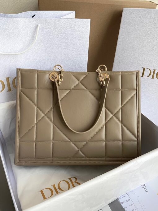 DIOR Essential Tote Bag. Original Quality Bag including gift box, care book, dust bag, authenticity card. A new House staple debuted at the Fall-Winter 2022-2023 ready-to-wear fashion show, the Dior Essential tote bag presents a functional design with modern elegance. Crafted in satin-finish calfskin, it is adorned with the Archicannage motif offering a new take on the iconic House topstitching. The spacious interior features three patch pockets and one zipped pocket to accommodate all of the essentials. Featuring leather and pale gold-finish metal chain top handles, the tote may be worn over the shoulder or carried by hand as an ideal daily companion. | CRIS&COCO Authentic Quality Designer Bag and Luxury Accessories