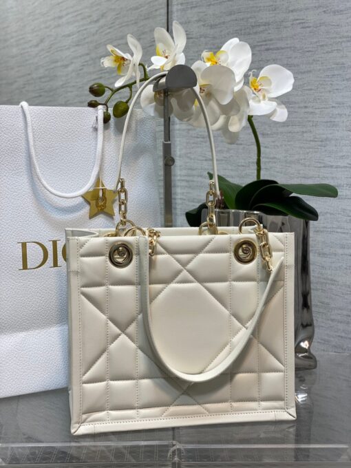 DIOR Essential Tote Bag. Original Quality Bag including gift box, care book, dust bag, authenticity card. A new House staple debuted at the Fall-Winter 2022-2023 ready-to-wear fashion show, the Dior Essential tote bag presents a functional design with modern elegance. Crafted in satin-finish calfskin, it is adorned with the Archicannage motif offering a new take on the iconic House topstitching. The spacious interior features three patch pockets and one zipped pocket to accommodate all of the essentials. Featuring leather and pale gold-finish metal chain top handles, the tote may be worn over the shoulder or carried by hand as an ideal daily companion. | CRIS&COCO Authentic Quality Designer Bag and Luxury Accessories