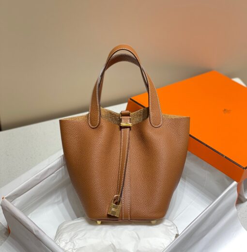 HERMÈS Picotin Lock Bag. Original Quality Bag including gift box, care book, dust bag, authenticity card. This timeless and minimalist bindle is inspired by horse feeders and is equipped with a discreet padlock. It takes its name from an old French term for the measure of oats given to a horse. The Picotin is the perfect equestrian escort, available in unlined leather that showcases the material; or in canvas and leather with outside pockets for a light, casual and functional wear. | CRIS&COCO Authentic Quality Designer Bags and Luxury Accessories