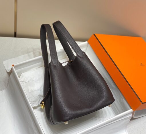 HERMÈS Picotin Lock Bag. Original Quality Bag including gift box, care book, dust bag, authenticity card. This timeless and minimalist bindle is inspired by horse feeders and is equipped with a discreet padlock. It takes its name from an old French term for the measure of oats given to a horse. The Picotin is the perfect equestrian escort, available in unlined leather that showcases the material; or in canvas and leather with outside pockets for a light, casual and functional wear. | CRIS&COCO Authentic Quality Designer Bags and Luxury Accessories