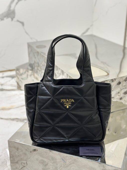 PRADA Nappa Tote Bag. High-End Quality Bag including gift box, care book, dust bag, authenticity card. An unusual triangle motif creates three-dimensional plays on this nappa-leather shopper bag, reinterpreting the iconic Prada shape. Defined by a versatile allure, the style is completed by a magnetic clasp and signature enameled-metal triangle logo. | CRIS AND COCO Authentic Quality Luxury Accessories