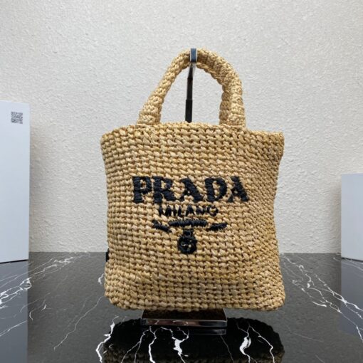 PRADA Small Crochet Tote Bag. Elevate Your Look with an Exquisite Tote Bag! This exquisite tote bag has a deconstructed design made of a light, natural material with a summery mood, raffia-effect yarn. Embroidered lettering logo decorates the front, and the emblematic triangle in enameled metal is the perfect finishing touch to the side. | CRIS&COCO Authentic Quality Designer Bags and Luxury Accessories