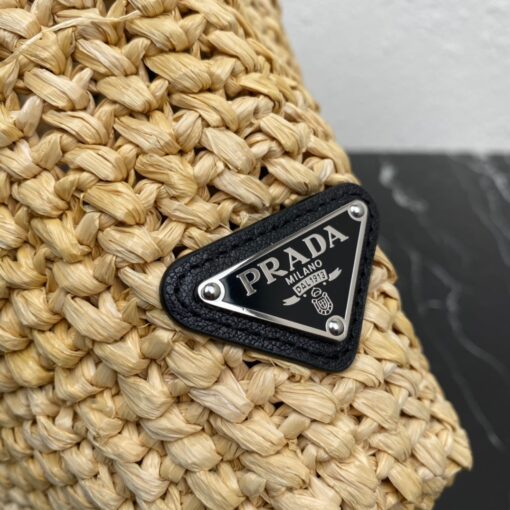 PRADA Small Crochet Tote Bag. Elevate Your Look with an Exquisite Tote Bag! This exquisite tote bag has a deconstructed design made of a light, natural material with a summery mood, raffia-effect yarn. Embroidered lettering logo decorates the front, and the emblematic triangle in enameled metal is the perfect finishing touch to the side. | CRIS&COCO Authentic Quality Designer Bags and Luxury Accessories