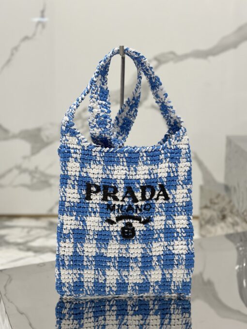 PRADA Crochet Bag- where refined logos meet natural raffia-inspired beauty.  Introducing a beautifully crafted tote bag, featuring a gentle, deconstructed design, elegantly crafted from raffia-effect yarn. This lightweight and natural material exudes a delightful summery vibe. The front adorns a sleek enameled metal triangle logo and delicately embroidered lettering logo, engaging in a captivating and harmonious aesthetic conversation. | CRIS&COCO Authentic Quality Designer Bags and Luxury Accessories