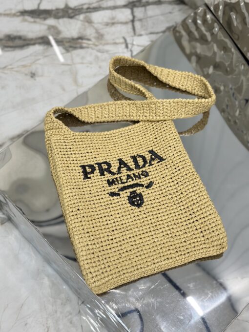 PRADA Crochet Bag- where refined logos meet natural raffia-inspired beauty.  Introducing a beautifully crafted tote bag, featuring a gentle, deconstructed design, elegantly crafted from raffia-effect yarn. This lightweight and natural material exudes a delightful summery vibe. The front adorns a sleek enameled metal triangle logo and delicately embroidered lettering logo, engaging in a captivating and harmonious aesthetic conversation. | CRIS&COCO Authentic Quality Designer Bags and Luxury Accessories