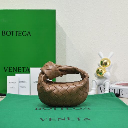 BOTTEGA VENETA Mini Jodie. Mini Marvel: Elevate Your Essentials. Introducing the BV Mini Jodie by Daniel Lee, a captivating embodiment of the mini bag trend infused with a captivating minimalist essence. True to the distinctive allure of the Jodie collection, this rendition showcases the iconic Intrecciato weave and the signature knot embellishment. Delicately compact, it effortlessly nestles under your arm akin to a charming baguette bag, yet offers ample space for your essentials such as your phone, cards, and keys. Despite its diminutive size, this mini bag radiates a vibrant aura through an array of lively hues, ensuring it leaves a memorable impression. | CRIS&COCO Authentic Quality Designer Bags and Luxury Accessories