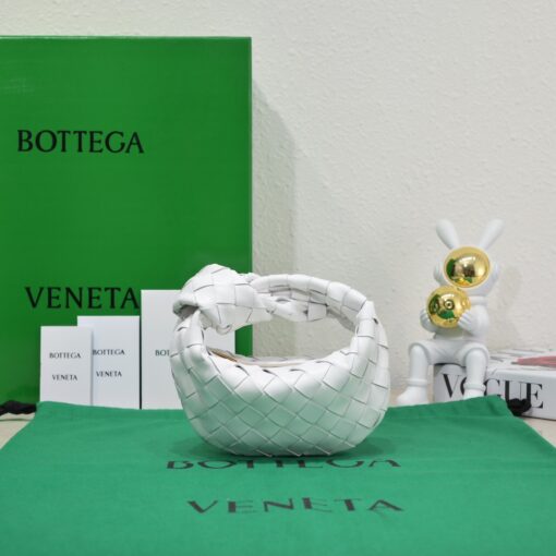 BOTTEGA VENETA Mini Jodie. Mini Marvel: Elevate Your Essentials. Introducing the BV Mini Jodie by Daniel Lee, a captivating embodiment of the mini bag trend infused with a captivating minimalist essence. True to the distinctive allure of the Jodie collection, this rendition showcases the iconic Intrecciato weave and the signature knot embellishment. Delicately compact, it effortlessly nestles under your arm akin to a charming baguette bag, yet offers ample space for your essentials such as your phone, cards, and keys. Despite its diminutive size, this mini bag radiates a vibrant aura through an array of lively hues, ensuring it leaves a memorable impression. | CRIS&COCO Authentic Quality Designer Bags and Luxury Accessories