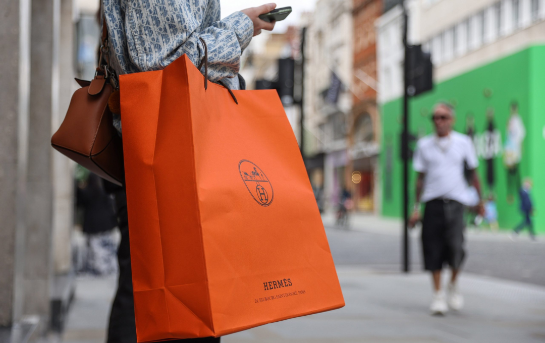 A stylish Hermès paper bag featuring the brand's signature orange color and logo, elegantly displayed against a clean background.