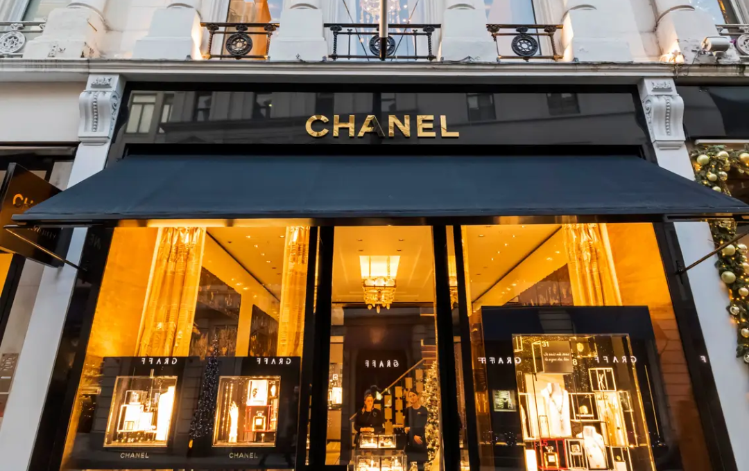 A chic exterior view of a Chanel boutique, showcasing the store’s elegant architecture, sophisticated window displays, and the iconic Chanel logo prominently displayed.