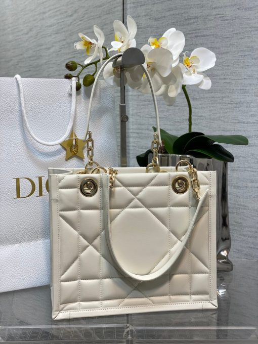 DIOR Essential Tote Bag. Original Quality Bag including gift box, care book, dust bag, authenticity card. A new House staple debuted at the Fall-Winter 2022-2023 ready-to-wear fashion show, the Dior Essential tote bag presents a functional design with modern elegance. Crafted in satin-finish calfskin, it is adorned with the Archicannage motif offering a new take on the iconic House topstitching. The spacious interior features three patch pockets and one zipped pocket to accommodate all of the essentials. Featuring leather and pale gold-finish metal chain top handles, the tote may be worn over the shoulder or carried by hand as an ideal daily companion.