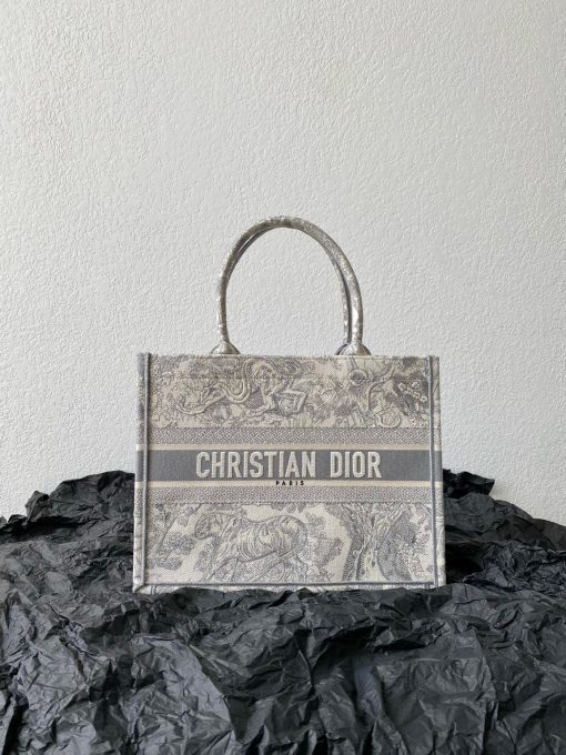 DIOR Book Tote. Original Quality Bag including gift box, care book, dust bag, authenticity card. This Book Tote is an original style introduced by Creative Director Maria Grazia Chiuri. This has become a staple of the Dior aesthetic. Ideally designed to carry all your daily essentials, the small shape is fully embroidered and the 'Christian Dior' signature on the front. This carryall is a perfect example of the Dior savoir-faire and also may be coordinated with a pouch or other small leather goods for a complete look.