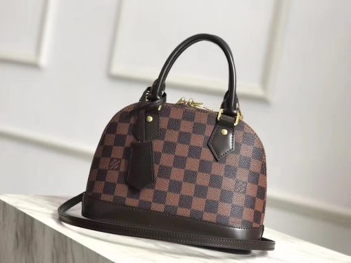 LOUIS VUITTON 'Alma' BB 2Way Bag. Original Quality Bag including gift box, care book, dust bag, authenticity card. This authentic quality bag is a fresh and elegant spin on a classic style that is perfect for all seasons. Crafted from LOUIS VUITTON brown coated canvas, this petite dome-shaped satchel features dual-rolled leather handles, Vachetta leather trims, protective base studs, leather clochette with key and zipper pull with LV logo lock charm and gold-tone hardware accents. Its all-around zip closure opens to a brown fabric-lined interior with a slip pocket for storing bare essentials. Its detachable strap allows this bag to be worn longer on the body for added versatility.