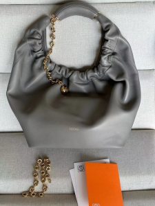 LOEWE Small Squeeze Bag: Where Elegance Meets Innovation in Luxurious Nappa Leather. The Squeeze bag embodies sophistication and femininity, crafted from luxurious nappa leather. It stands as a masterpiece, seamlessly blending traditional craftsmanship, innovative research, and distinctive design elements. The bag features a surprisingly lightweight ruched body, complemented by an adjustable donut chain and a tactile, squeezable handle. This particular version showcases the elegance of nappa lambskin in a compact size, adding an extra touch of refinement to its allure.