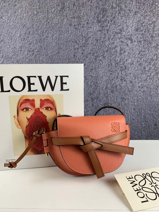 LOEWE Gate Mini Grained-Leather Cross-Body Bag. Original Quality Bag. Authentic Style. Genuine Calf Leather. Metal Hardware. Authentic Packaging. Original Quality Dust Bag. Loewe brings signature finesse to the micro-mini bag trend with this tiny red iteration of its coveted Gate style. The bag takes inspiration from countryside gate latch fastenings to create this grained-leather Gate cross-body bag. It's crafted to a half-moon shape with a long shoulder strap that is finished with black lacquered edges, then opens to reveal a suede interior with a single slip pocket.