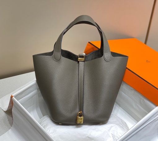 HERMÈS Picotin Lock Bag. Original Quality Bag including gift box, care book, dust bag, authenticity card. This timeless and minimalist bindle is inspired by horse feeders and is equipped with a discreet padlock. It takes its name from an old French term for the measure of oats given to a horse. The Picotin is the perfect equestrian escort, available in unlined leather that showcases the material; or in canvas and leather with outside pockets for a light, casual and functional wear.