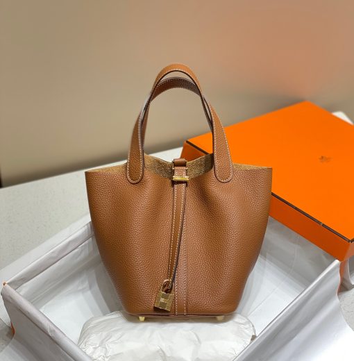 HERMÈS Picotin Lock Bag. Original Quality Bag including gift box, care book, dust bag, authenticity card. This timeless and minimalist bindle is inspired by horse feeders and is equipped with a discreet padlock. It takes its name from an old French term for the measure of oats given to a horse. The Picotin is the perfect equestrian escort, available in unlined leather that showcases the material; or in canvas and leather with outside pockets for a light, casual and functional wear.