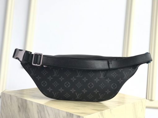 LOUIS VUITTON Discovery Bum Bag. Combining casual sophistication with contemporary practicality, the Discovery Bumbag is the perfect city companion. It is fashioned from Monogram Eclipse canvas/Monogram Shadow leather and adorned with zipped pockets on the front and back for easy access. With its adjustable belt and body-friendly design, it can be worn stylishly slung across the chest, draped over the shoulder or simply strapped around the waist.