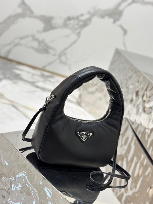 PRADA Soft Padded Mini Bag. Original Quality Bag including gift box, care book, dust bag, authenticity card. A harmonious, bold silhouette characterizes this mini-bag made of padded leather accented with the detachable, adjustable shoulder strap. Defined by its versatile allure, the accessory has a zipper closure and is decorated with the emblematic enameled metal triangle logo.