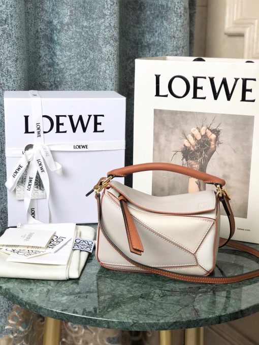 LOEWE Mini Puzzle Bag. Original Quality Bag including gift box, care book, dust bag, authenticity card. The Puzzle bag is the debut bag for LOEWE by Creative Director Jonathan Anderson. A cuboid shape and precise cutting technique create Puzzle’s distinctive geometric lines. This mini version is crafted in contrasting calfskins.