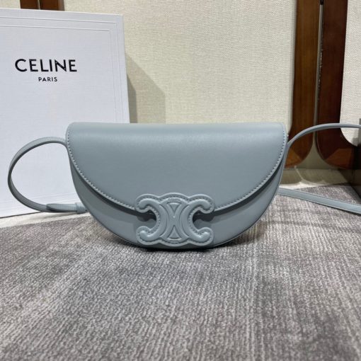 CELINE Besace Cuir Triomphe. High-End Quality Bag including gift box, care book, dust bag, authenticity card. Offered in the half-moon shape that’s all the rage now, the significantly wider format measures 23 cm from tip to tip. Each bag opens via a snap button closure to reveal a roomy interior compartment and a flat inner pocket. Another noticeable feature of the bag lies in the oversized Triomphe logo. With tonal stitching along the edges, the logo on the Triomphe Canvas comes in contrasting Tan leather. For a monochrome effect, go for the Ice Blue and Tan with logos in matching colours.