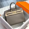 HERMÈS Birkin. Exquisite Craftsmanship and Timeless Elegance: Discover the Allure of the HERMES Birkin Bag Large Leather Top Handle. Designed with the actress Jane Birkin in mind, the Birkin bag is a contemporary development of the Kelly bag. Created based on Jane's suggestions, it was architected to be more significant to fit modern women's fast-paced life, with several minor yet outstanding adaptations, such as the elongated top handles. The French Birkin 30 bag is a classic touch of elegance to your look! The accessory features a trapeze body, a pebbled leather texture, a hanging key fob, gold-tone hardware, round top handles, a padlock fastening detail, a foldover top with twist-lock closure, a front center logo stamp, an internal zipped pocket, and purse feet.