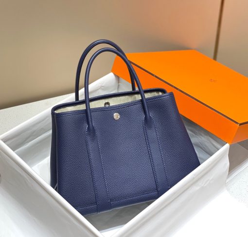 HERMÈS Garden Party: Style for Every Occasion. This Garden Party tote is the perfect blend of style and practicality. This chic and sporty bag is designed for every occasion, whether spending the day amongst the hustle and bustle of the city or enjoying a peaceful weekend in the countryside. Crafted with both leather and canvas, it's the perfect choice for whatever your destination. Not only is it spacious enough to hold your everyday essentials, but it also features Clou de Selle snap closures on the sides for added convenience. This snap that allows the bag to be just the right amount of malleable; to expand and create extra interior space to accommodate larger, or more items at once. Wherever your adventures take you, this exclusive HERMÈS tote will accompany you every step of the way.