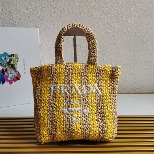 PRADA Small Crochet Tote Bag. Elevate Your Look with an Exquisite Tote Bag! This exquisite tote bag has a deconstructed design made of a light, natural material with a summery mood, raffia-effect yarn. Embroidered lettering logo decorates the front, and the emblematic triangle in enameled metal is the perfect finishing touch to the side.