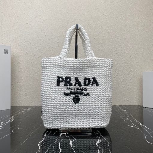 PRADA Small Crochet Tote Bag. Elevate Your Look with an Exquisite Tote Bag! This exquisite tote bag has a deconstructed design made of a light, natural material with a summery mood, raffia-effect yarn. Embroidered lettering logo decorates the front, and the emblematic triangle in enameled metal is the perfect finishing touch to the side.