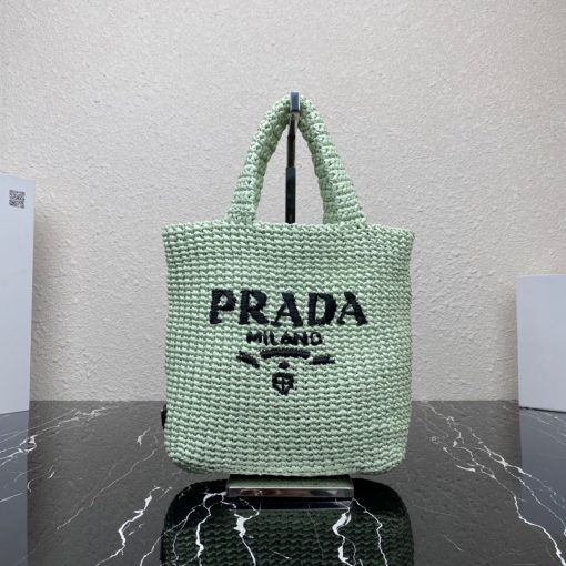 PRADA Small Crochet Tote Bag. Elevate Your Look with an Exquisite Tote Bag! This exquisite tote bag has a deconstructed design made of a light, natural material with a summery mood, raffia-effect yarn. Embroidered lettering logo decorates the front, and the emblematic triangle in enameled metal is the perfect finishing touch to the side.