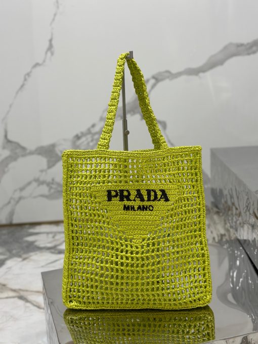 PRADA Crochet Tote Bag. Elevate your style with Prada's signature tote bag. This tote bag is the perfect addition to any summer wardrobe! Adorned with Prada's iconic triangle logo and embroidered lettering, its soft, deconstructed design is made with a light and natural raffia-effect yarn. It's sure to add an elevated touch to your ensemble.