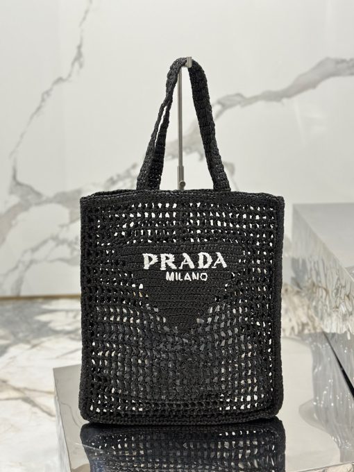 PRADA Crochet Tote Bag. Elevate your style with Prada's signature tote bag. This tote bag is the perfect addition to any summer wardrobe! Adorned with Prada's iconic triangle logo and embroidered lettering, its soft, deconstructed design is made with a light and natural raffia-effect yarn. It's sure to add an elevated touch to your ensemble.