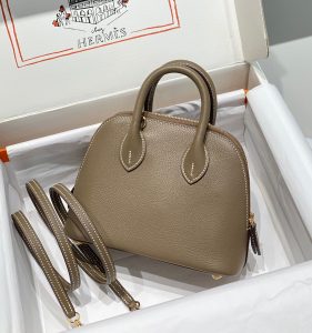HERMÈS Bolide 1923 Mini. Timeless Elegance, Unparalleled Convenience: The Bolide Bag – A Journey in Every Stitch. Created in 1923 with the discerning needs of elite drivers and seasoned long-distance travelers in mind, this globe-trotting bag effortlessly finds its place within any automobile trunk. Its iconic round-angled shape owes its origins to the zip fastener, a novel invention introduced to France by Émile Hermès in the late 1910s, and this innovative feature enables swift access to its contents. The Bolide bag is available in various sizes, including a travel-sized version, and a range of handbag options, offering both style and functionality to its fortunate owners.