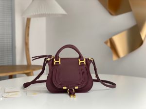 CHLOÉ Marcie Mini Double Carry Bag: Elegance in Miniature. Introducing a charming, petite rendition of the iconic Marcie handbag, this mini double carry bag exudes elegance with its meticulous craftsmanship in grained calfskin. Its clean, sleek lines and gracefully contoured design elevate the relaxed, slouchy silhouette, while the hand-wrapped leather handles impart an artisanal touch. The addition of metallic buckles bestows a polished and refined finish to this exquisite creation. Equipped with both double handles and a long, detachable shoulder strap, this mini bag epitomizes versatility, making it a must-have accessory for any occasion.