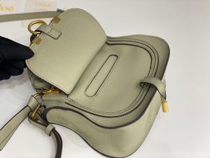 CHLOÉ Marcie Mini Double Carry Bag: Elegance in Miniature. Introducing a charming, petite rendition of the iconic Marcie handbag, this mini double carry bag exudes elegance with its meticulous craftsmanship in grained calfskin. Its clean, sleek lines and gracefully contoured design elevate the relaxed, slouchy silhouette, while the hand-wrapped leather handles impart an artisanal touch. The addition of metallic buckles bestows a polished and refined finish to this exquisite creation. Equipped with both double handles and a long, detachable shoulder strap, this mini bag epitomizes versatility, making it a must-have accessory for any occasion.