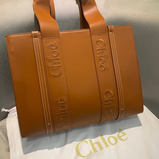 CHLOÉ Woody Tote Bag.  Original Quality Bag including gift box, care book, dust bag, authenticity card. Crafted from smooth calfskin for a natural look with a unique, luxurious feel, this Woody tote bag is a soft day-to-evening bag with a long, removable strap in addition to the top handles. The roomy inside compartment includes a practical flat pocket in leather for an elevated touch. Linen lining matches a refined finish with a lower environmental impact. The Woody line is characterised by the signature Chloé logo carried over from the Maison's iconic mules. It showcases a modern, minimalist silhouette.