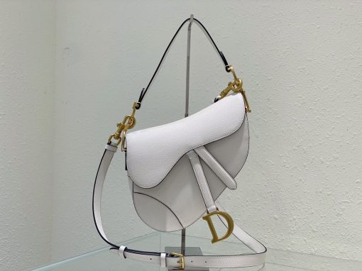 DIOR Saddle Bag With Strap. Original Quality Bag including gift box, care book, dust bag, authenticity card. Maria Grazia Chiuri brings a fresh update to the iconic Saddle bag. Crafted in grained calfskin, the legendary design features a Saddle flap with a magnetic 'D' stirrup clasp, as well as an antique gold-finish metal 'CD' signature on either side of the strap. Featuring a thin, adjustable and removable shoulder strap, the Saddle bag may be carried by hand, worn over the shoulder or crossbody.