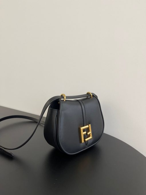 FENDI C’mon Mini. Embrace Elegance: Stefano Pilati's Curvaceous Creation. A petite satchel bag, graced with graceful, feminine curves, represents a masterpiece from the illustrious collection envisioned by the renowned Stefano Pilati. Fashioned from sumptuously smooth leather, this exquisite piece is adorned with meticulously embossed accents and edges, culminating in a striking FF logo proudly showcased on its elegant flap.