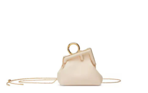 Stylish woman sipping coffee outdoors, wearing a white FENDI First Nano Charm bag.