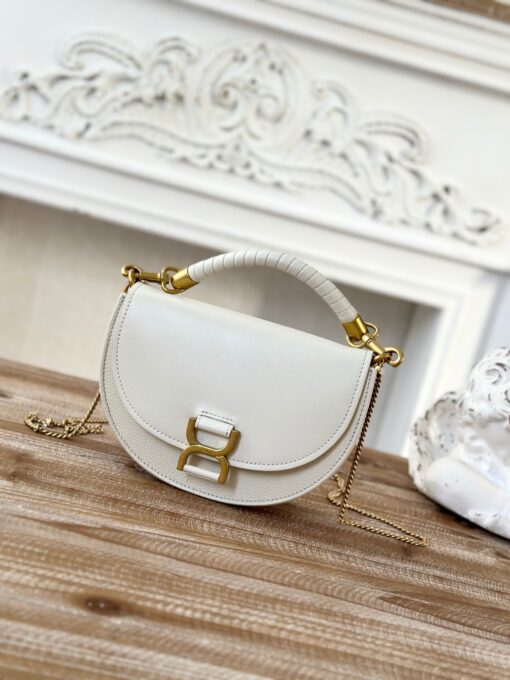 Marcie Chain Flap Bag. Authentic quality luxury bag crafted in genuine leather comes with authenticity card, dust bag and gift bag. Elevating Iconic Elegance: Marcie Line Redefined. Experience a fresh take on *loé's iconic Marcie line with this exquisite chain flap bag, meticulously crafted from a captivating blend of nappa lambskin, grained calfskin, and sumptuous suede. The line's signature hardware undergoes a graceful transformation, now adorned with *loé's engraved jewelry hallmark, adorning the flap with sophistication. An intricately hand-braided top handle pays homage to another hallmark Marcie feature, while a gracefully extended chain strap adds a refined touch. Whether you choose to drape it over your shoulder or wear it cross-body during the day, or opt to detach the strap and carry it by hand for a sophisticated evening ensemble, this flap bag is a versatile masterpiece. *loé's Marcie bag line effortlessly melds a feminine aesthetic with the free-spirited vibe of the '70s. An equestrian-inspired allure takes center stage, elevated by the allure of gleaming gold-toned hardware, resulting in a distinctly feminine yet timelessly chic look.