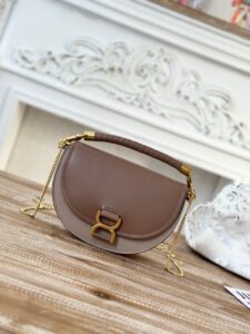 Marcie Chain Flap Bag. Authentic quality luxury bag crafted in genuine leather comes with authenticity card, dust bag and gift bag. Elevating Iconic Elegance: Marcie Line Redefined. Experience a fresh take on *loé's iconic Marcie line with this exquisite chain flap bag, meticulously crafted from a captivating blend of nappa lambskin, grained calfskin, and sumptuous suede. The line's signature hardware undergoes a graceful transformation, now adorned with *loé's engraved jewelry hallmark, adorning the flap with sophistication. An intricately hand-braided top handle pays homage to another hallmark Marcie feature, while a gracefully extended chain strap adds a refined touch. Whether you choose to drape it over your shoulder or wear it cross-body during the day, or opt to detach the strap and carry it by hand for a sophisticated evening ensemble, this flap bag is a versatile masterpiece. *loé's Marcie bag line effortlessly melds a feminine aesthetic with the free-spirited vibe of the '70s. An equestrian-inspired allure takes center stage, elevated by the allure of gleaming gold-toned hardware, resulting in a distinctly feminine yet timelessly chic look. | PURSE POP UP LIVE Marcie Chain Flap Bag. Authentic quality luxury bag crafted in genuine leather comes with authenticity card, dust bag and gift bag. Elevating Iconic Elegance: Marcie Line Redefined. Experience a fresh take on *loé's iconic Marcie line with this exquisite chain flap bag, meticulously crafted from a captivating blend of nappa lambskin, grained calfskin, and sumptuous suede. The line's signature hardware undergoes a graceful transformation, now adorned with *loé's engraved jewelry hallmark, adorning the flap with sophistication. An intricately hand-braided top handle pays homage to another hallmark Marcie feature, while a gracefully extended chain strap adds a refined touch. Whether you choose to drape it over your shoulder or wear it cross-body during the day, or opt to detach the strap and carry it by hand for a sophisticated evening ensemble, this flap bag is a versatile masterpiece. *loé's Marcie bag line effortlessly melds a feminine aesthetic with the free-spirited vibe of the '70s. An equestrian-inspired allure takes center stage, elevated by the allure of gleaming gold-toned hardware, resulting in a distinctly feminine yet timelessly chic look.