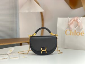 Marcie Chain Flap Bag. Authentic quality luxury bag crafted in genuine leather comes with authenticity card, dust bag and gift bag. Elevating Iconic Elegance: Marcie Line Redefined. Experience a fresh take on *loé's iconic Marcie line with this exquisite chain flap bag, meticulously crafted from a captivating blend of nappa lambskin, grained calfskin, and sumptuous suede. The line's signature hardware undergoes a graceful transformation, now adorned with *loé's engraved jewelry hallmark, adorning the flap with sophistication. An intricately hand-braided top handle pays homage to another hallmark Marcie feature, while a gracefully extended chain strap adds a refined touch. Whether you choose to drape it over your shoulder or wear it cross-body during the day, or opt to detach the strap and carry it by hand for a sophisticated evening ensemble, this flap bag is a versatile masterpiece. *loé's Marcie bag line effortlessly melds a feminine aesthetic with the free-spirited vibe of the '70s. An equestrian-inspired allure takes center stage, elevated by the allure of gleaming gold-toned hardware, resulting in a distinctly feminine yet timelessly chic look. | PURSE POP UP LIVE Marcie Chain Flap Bag. Authentic quality luxury bag crafted in genuine leather comes with authenticity card, dust bag and gift bag. Elevating Iconic Elegance: Marcie Line Redefined. Experience a fresh take on *loé's iconic Marcie line with this exquisite chain flap bag, meticulously crafted from a captivating blend of nappa lambskin, grained calfskin, and sumptuous suede. The line's signature hardware undergoes a graceful transformation, now adorned with *loé's engraved jewelry hallmark, adorning the flap with sophistication. An intricately hand-braided top handle pays homage to another hallmark Marcie feature, while a gracefully extended chain strap adds a refined touch. Whether you choose to drape it over your shoulder or wear it cross-body during the day, or opt to detach the strap and carry it by hand for a sophisticated evening ensemble, this flap bag is a versatile masterpiece. *loé's Marcie bag line effortlessly melds a feminine aesthetic with the free-spirited vibe of the '70s. An equestrian-inspired allure takes center stage, elevated by the allure of gleaming gold-toned hardware, resulting in a distinctly feminine yet timelessly chic look.